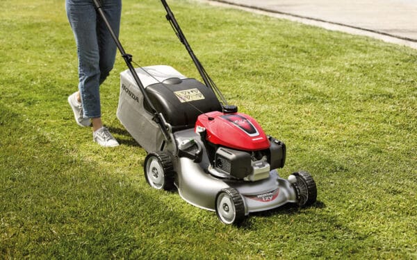 En person kör en Honda gräsklippare HRG466 PKEH på grön gräsmatta