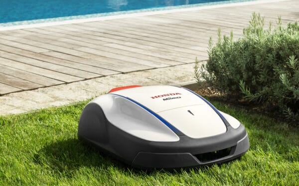 Honda Miimo robotgräsklippare klipper en grön gräsmatta bredvid ett trädäck och en pool