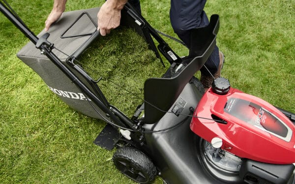 Händer öppnar uppsamlaren på en gräsklippare från Honda, HRN536 VKEA