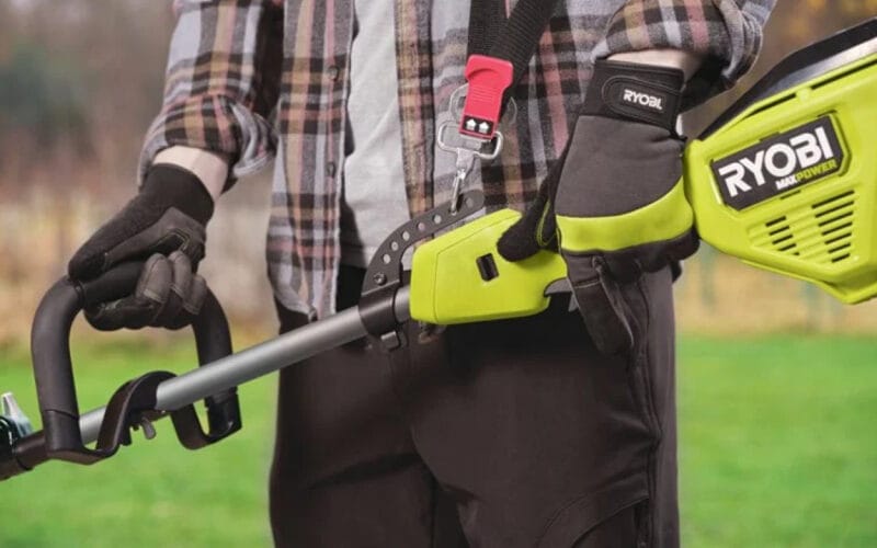 En närbild på en person som håller i en RYOBI grästrimmer RY36LTX40A-0